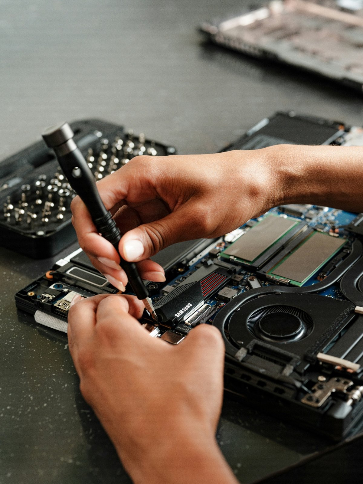 Hands repairing a laptop with a precision screwdriver